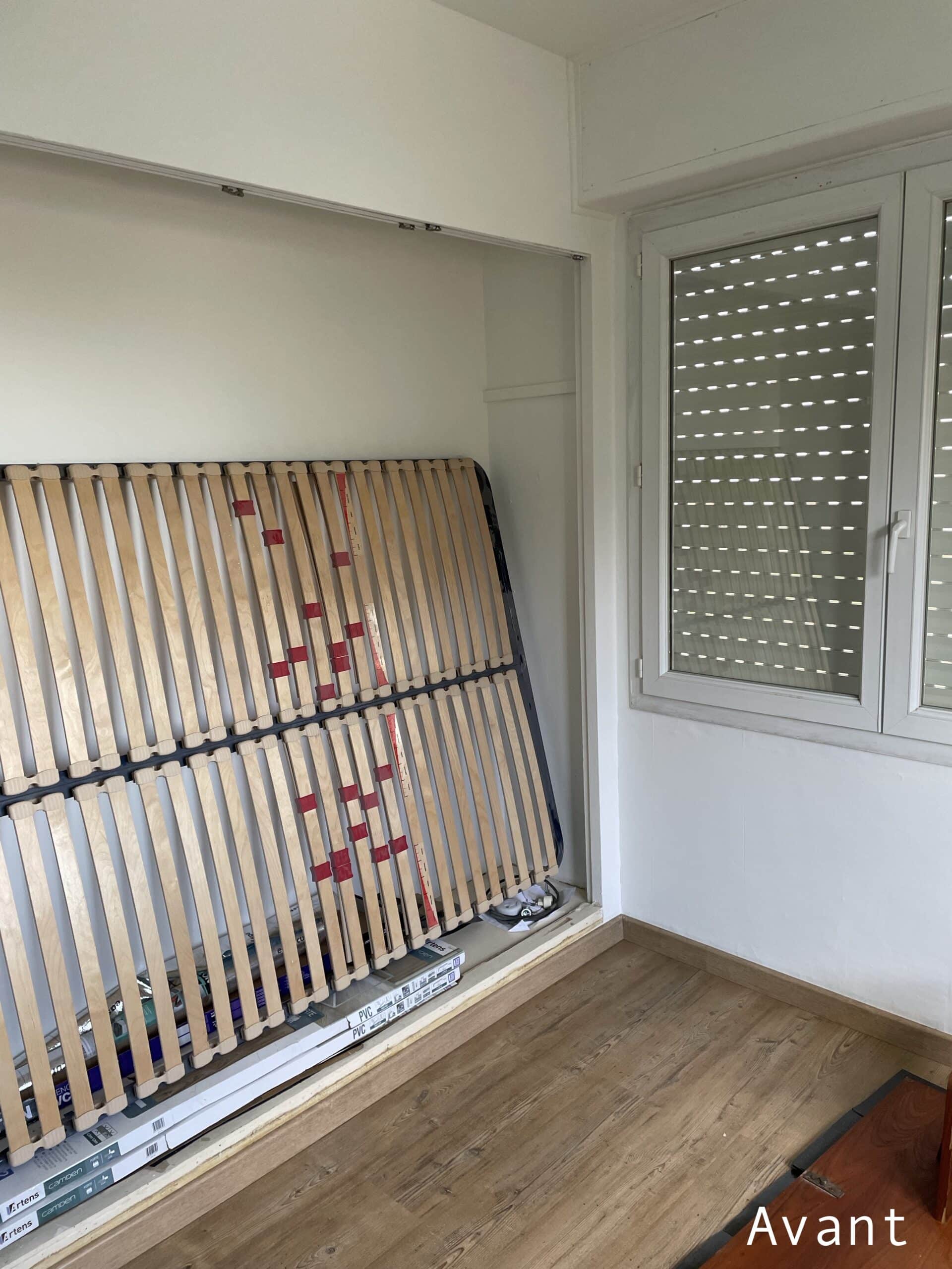 Sommier à lattes appuyé dans un renfoncement de mur, pièce vide en rénovation avec fenêtre. Texte 'Avant'.
