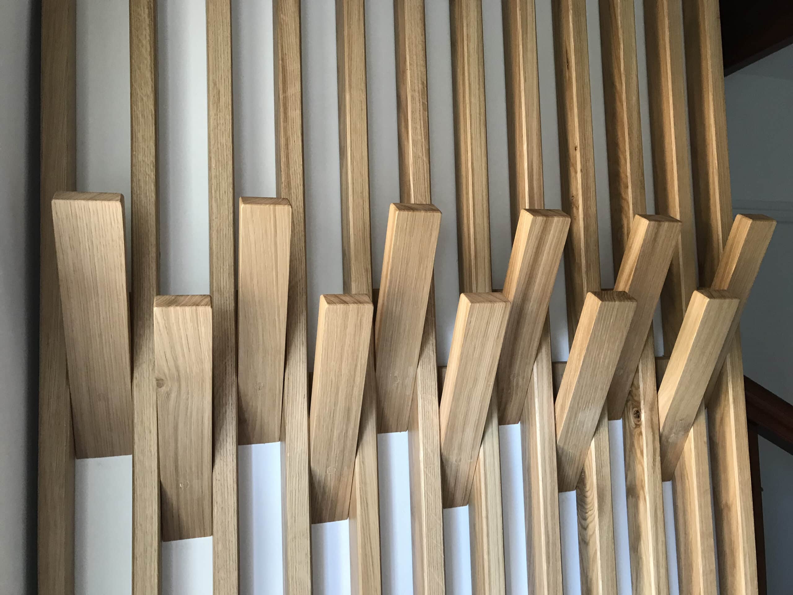 Portemanteau mural en bois clair à lattes verticales.