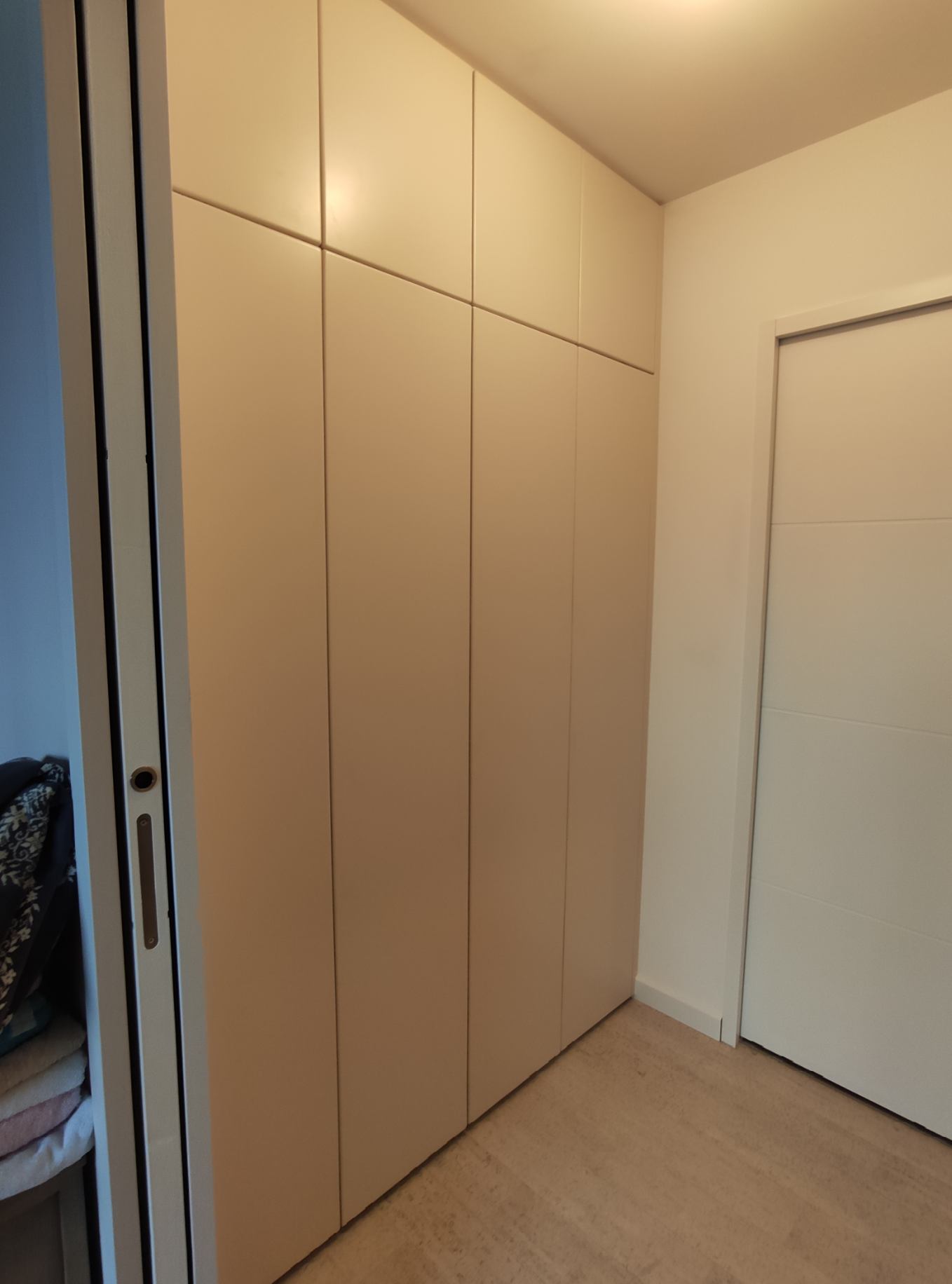 Armoire encastrée beige du sol au plafond au design minimaliste dans un intérieur moderne.