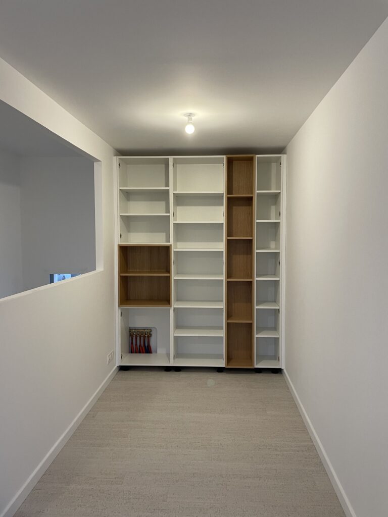 Bibliothèque sur mesure blanc et bois : design épuré Bibliothèque sur mesure blanche et bois dans un espace moderne et épuré.