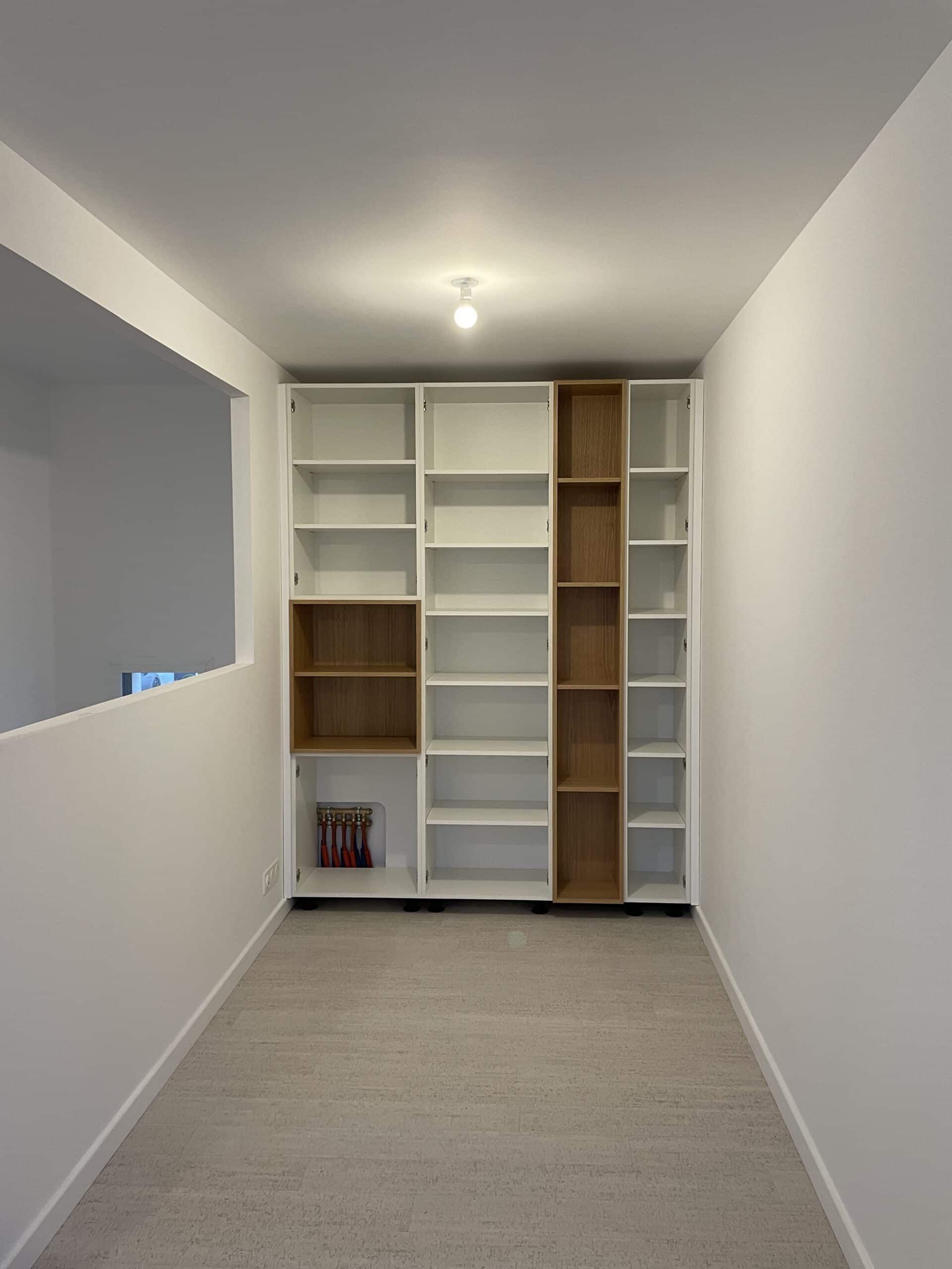 Bibliothèque sur mesure blanche et bois dans un espace moderne et épuré.