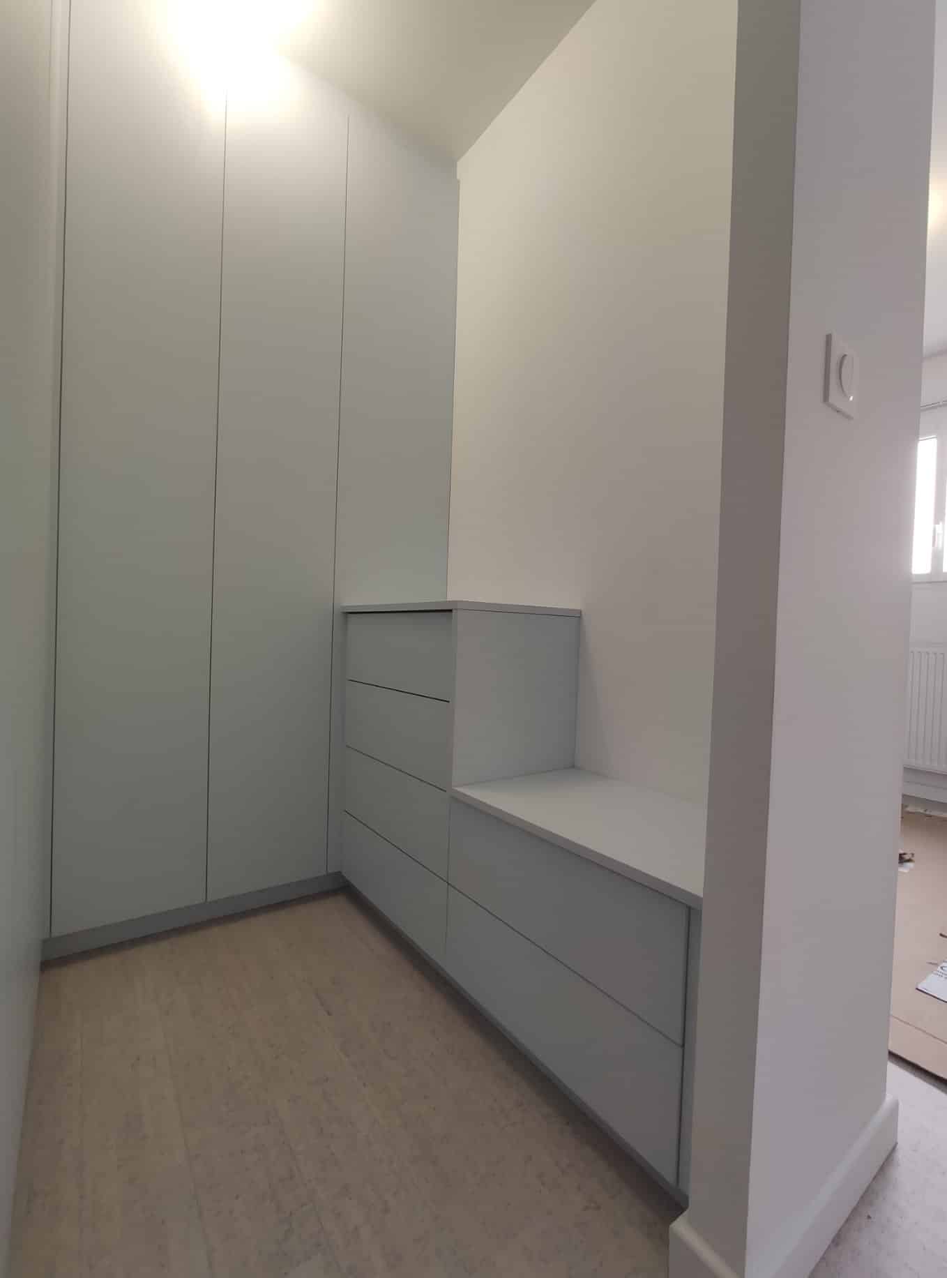 Dressing sur mesure blanc avec placards toute hauteur et commode à tiroirs intégrée dans un coin moderne.