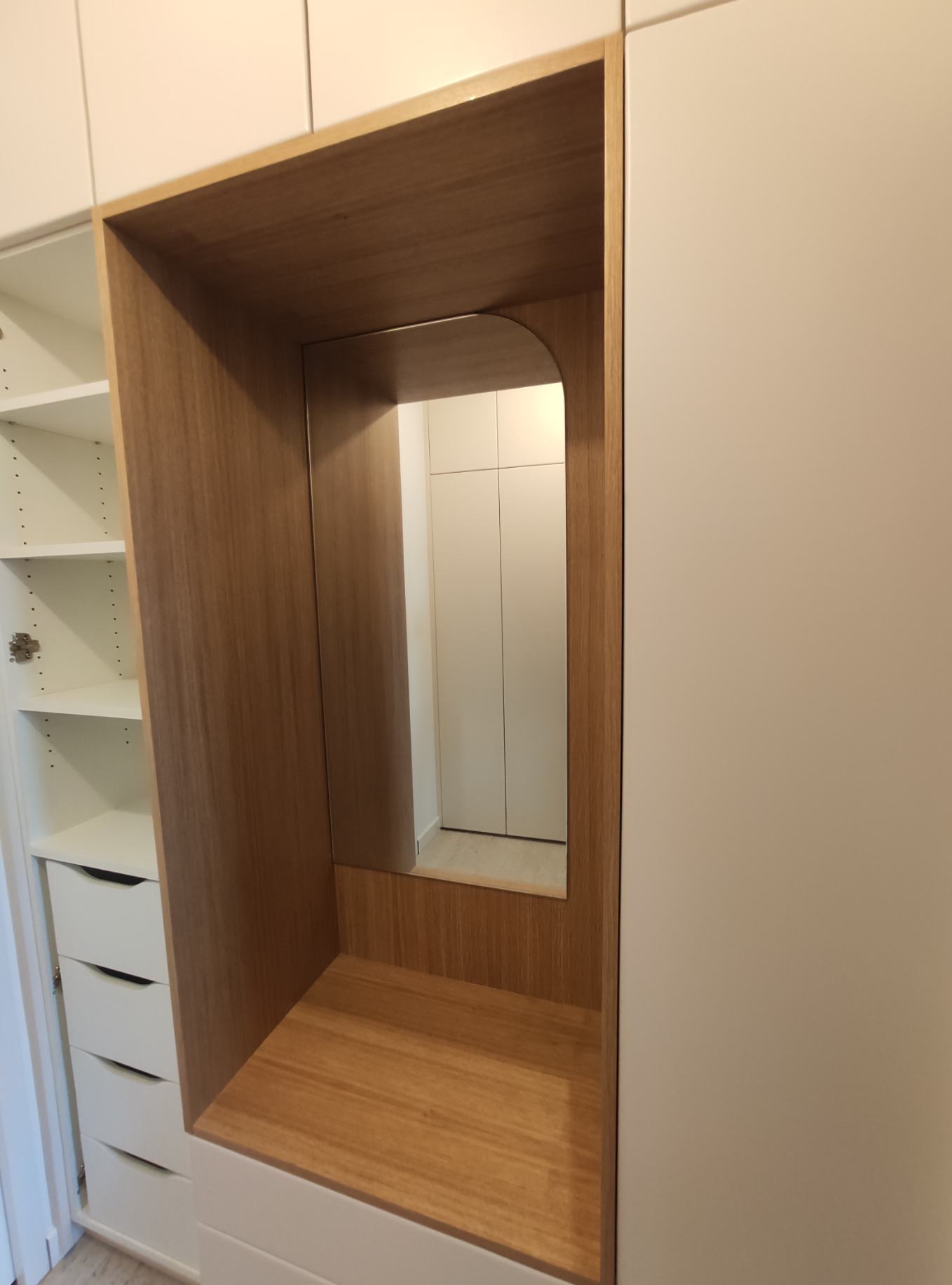 Placard sur mesure en bois et blanc avec miroir intégré, étagères ouvertes et tiroirs de rangement modernes.